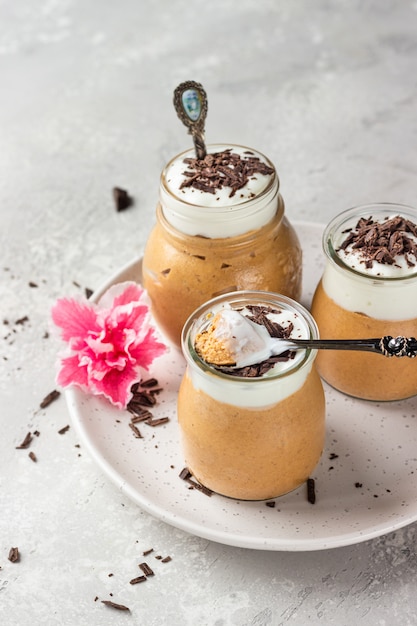 Mousse au chocolat avec crème fouettée et morceaux de chocolat dans des verres à portion