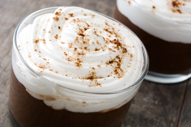 Mousse au chocolat avec crème en verre sur table en bois se bouchent