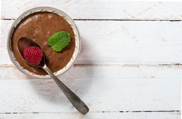 Mousse au chocolat maison à la framboise sur une surface en bois blanche