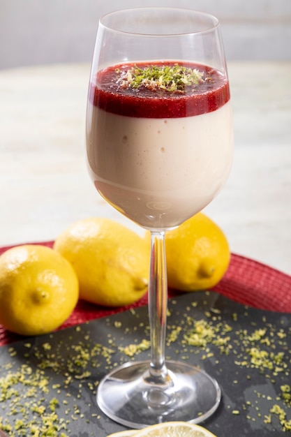 Mousse au citron dans un bol en cristal avec garniture de gelée de fraise et zeste de citron.