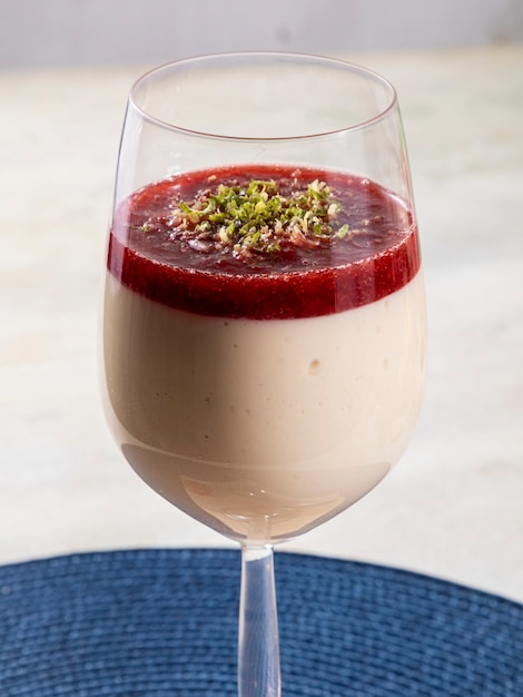 Mousse au citron dans un bol en cristal avec garniture de gelée de fraise et zeste de citron.