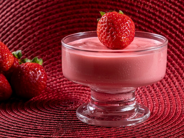 Mousse aux fraises savoureuse en verre avec fraise sur le dessus.
