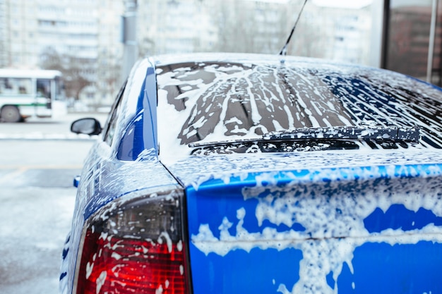 De la mousse de savon coule sur le verre. lave-auto en libre-service