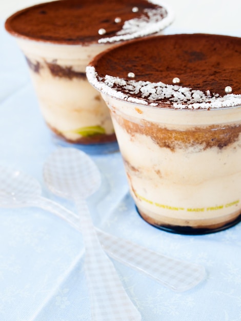 Mousse tiramisu avec décoration personnalisée servie dans un gobelet en plastique.