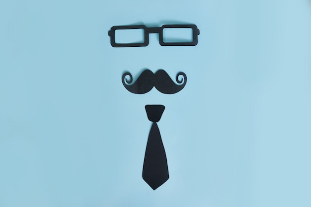 Moustache d&#39;homme décoratif, lunettes noires et noeud papillon sur un bois bleu clair