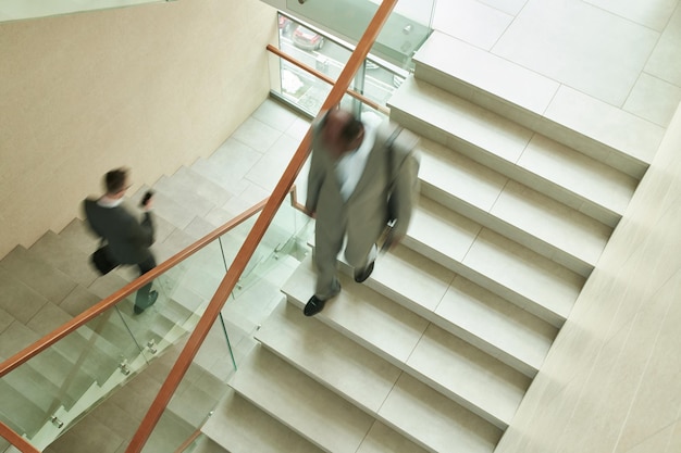 Mouvement flou de deux employés masculins multiculturels quittant le centre de bureau