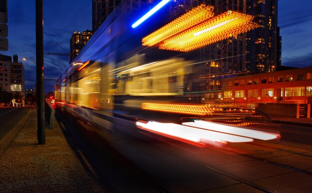 Photo mouvement flou du train dans une ville éclairée la nuit