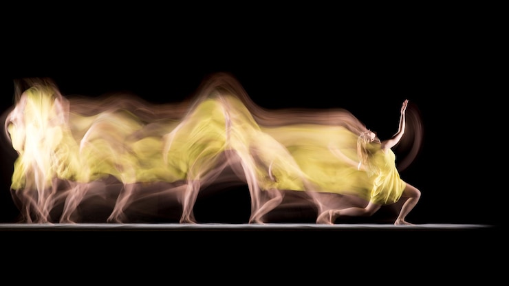 Photo mouvement flou d'une femme dansant sur un fond noir