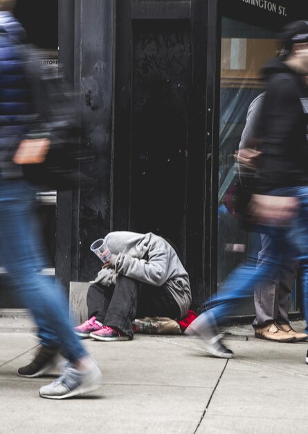 Mouvement flou des gens qui marchent par mendiant mendiant sur le trottoir