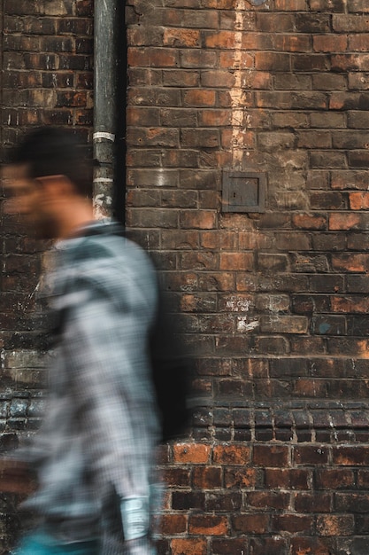 Photo mouvement flou d'un homme marchant contre un mur de briques