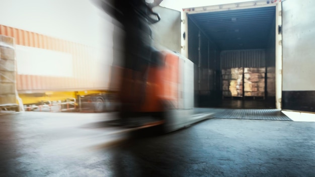 Mouvement flou des travailleurs conduisant un chariot élévateur déchargeant des palettes de fret dans des camions porte-conteneurs expédiant des marchandises