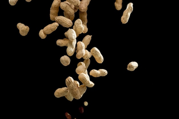 Mouvement de gel réaliste de cacahuètes volantes sur fond noir.