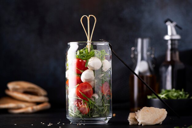 Mozzarella aux tomates cerises et roquette dans un bocal en verre sur fond sombre