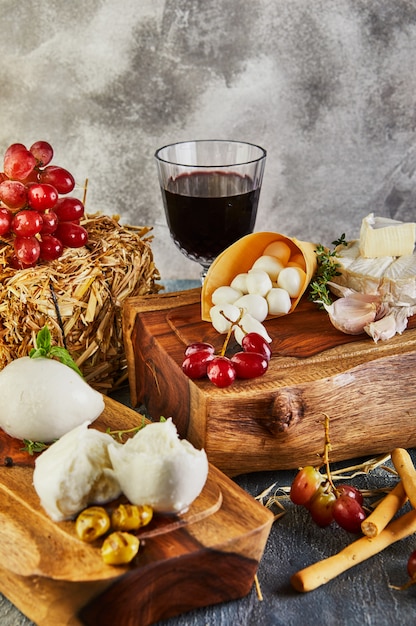 Mozzarella baby brie et mozzarella murale à l'ail et aux raisins et un verre de vin sur un support en bois