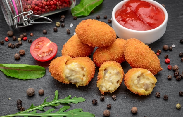 Mozzarella frite, bouchées de fromage cheddar, boules de ketchup sur planche de pierre rustique