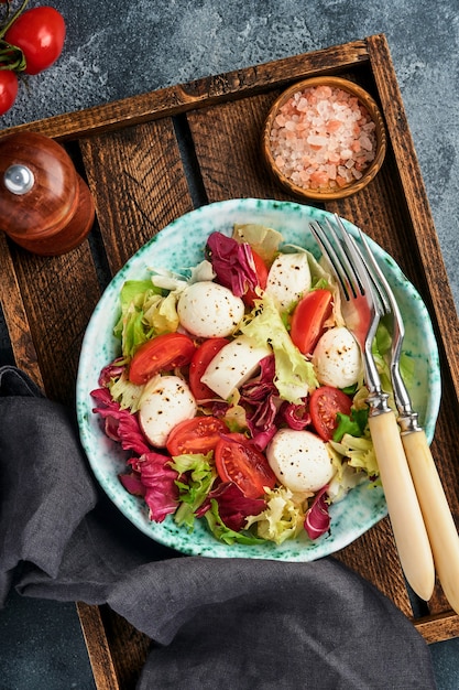 Mozzarella, tomate et mélange de feuilles de salade fraîches, fond sombre, vue de dessus. Maquette.