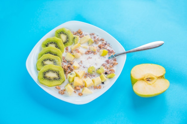 Muesli au kiwi et pomme au lait sur fond bleu