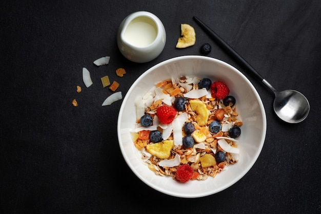 Muesli au lait servi dans un bol sur fond sombre.