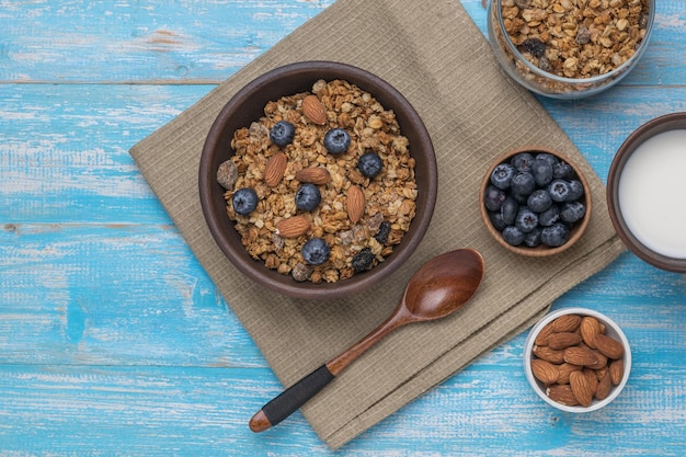 Muesli aux baies et noix dans un bol en argile sur une table bleue rustique. Petit-déjeuner végétarien sain. Mise à plat.