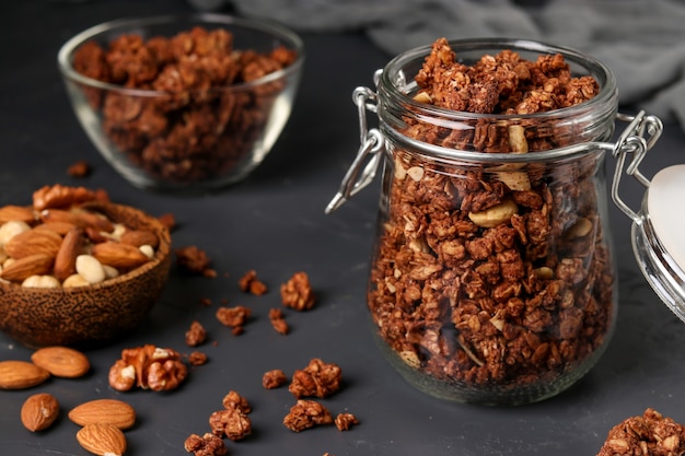 muesli croustillant granola avec du miel naturel, du chocolat et des noix dans un bocal et un bol en verre