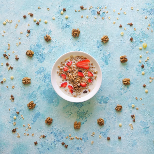 Muesli dans un bol avec des fraises sur une table bleue. Granola aux fraises.