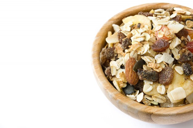 Muesli et fruits secs dans un bol en bois isolé sur blanc