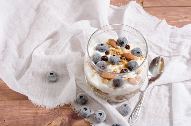 Muesli avec yaourt naturel, myrtille, noix et fruits secs dans un bocal en verre