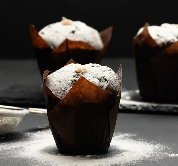 Muffin au chocolat au four avec garniture à la crème saupoudrée de sucre en poudre sur un tabl noir