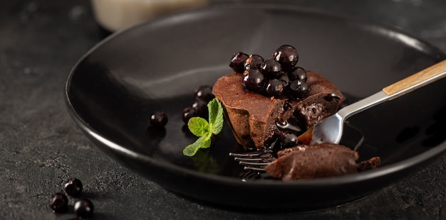 Muffin au chocolat avec des bleuets en plaque noire sur fond sombre avec du café