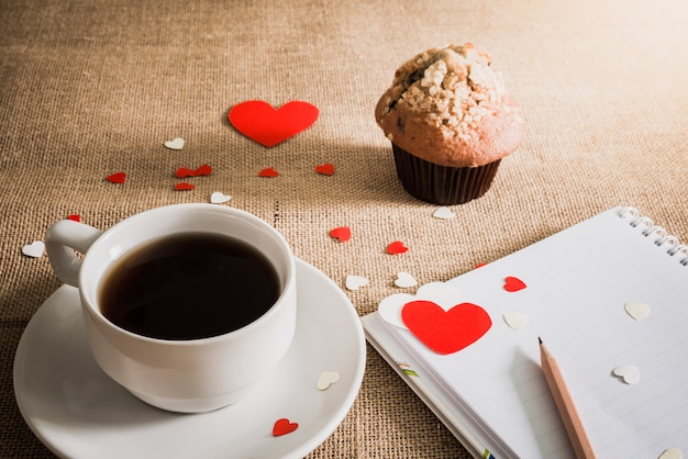 Muffin au chocolat et café et cœurs sur des textures de sacs en toile