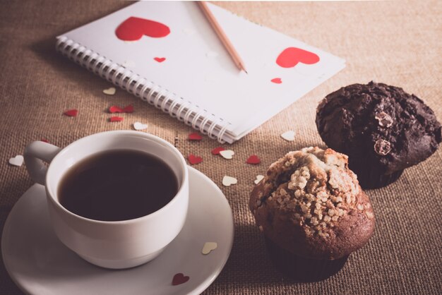 Muffin au chocolat et café et coeurs sur des textures de sacs