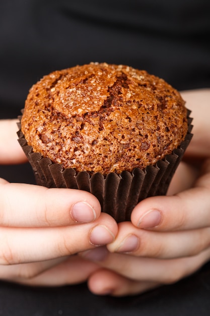 Muffin au chocolat fait maison avec une croûte de caramel (sucre) dans les mains des enfants