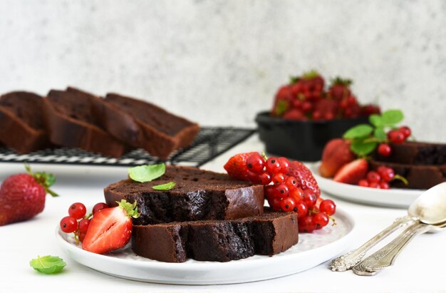 Muffin au chocolat avec fraises et groseilles sur fond de béton clair. Morceaux de gâteau. Tarte aux brownies.