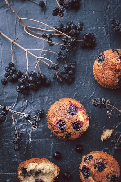 Muffin aux groseilles sur fond sombre à côté des baies sur les branches. dans un style rustique. style sombre