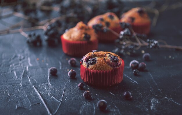 Muffin aux groseilles sur fond sombre à côté des baies sur les branches. dans un style rustique. style sombre