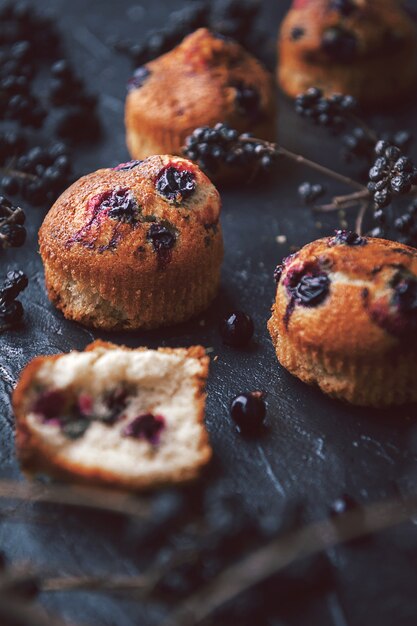 Muffin aux groseilles sur fond sombre à côté des baies sur les branches. dans un style rustique. style sombre