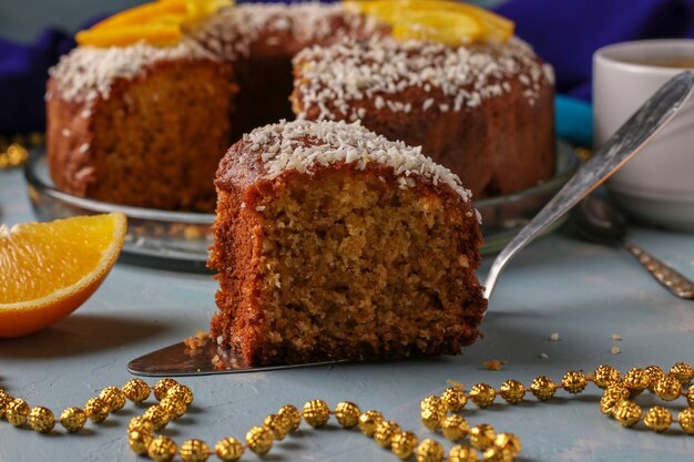 Muffin fait maison avec des oranges saupoudrées de flocons de noix de coco sur une surface bleu clair