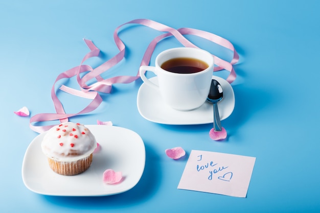 Muffin avec glaçage sur une assiette et une tasse