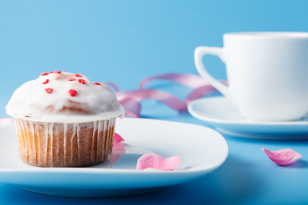 Muffin avec glaçage sur une assiette et une tasse