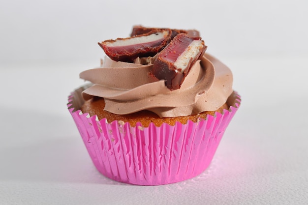 Muffin à la vanille avec crème fouettée au chocolat et bonbons sur le dessus.