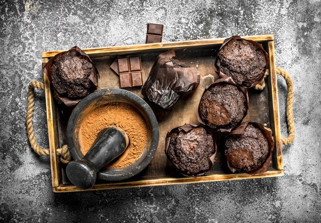 Muffins au chocolat avec du cacao sur l'ancien plateau sur table rustique.