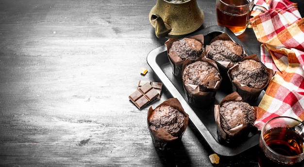 Muffins au chocolat avec du thé frais sur tableau noir.