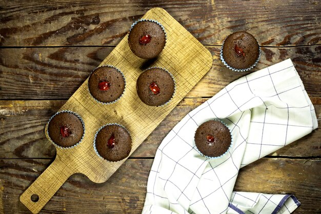 des muffins au chocolat fait maison décorés de cerises confisquées sur une table en bois