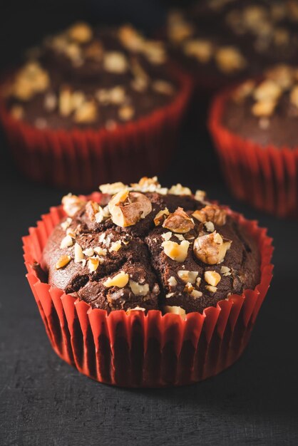 Muffins au chocolat faits maison ou cupcakes saupoudrés de noix sur fond sombre