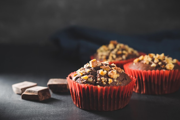 Muffins au chocolat faits maison ou cupcakes saupoudrés de noix sur fond sombre