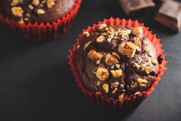 Muffins au chocolat faits maison ou cupcakes saupoudrés de noix sur fond sombre