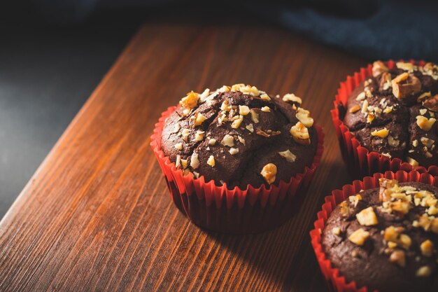 Muffins au chocolat faits maison ou cupcakes saupoudrés de noix sur une planche de bois