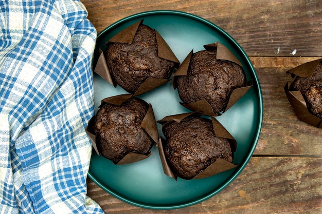 muffins au chocolat faits maison ou madeleine dans une assiette verte sur une table en bois