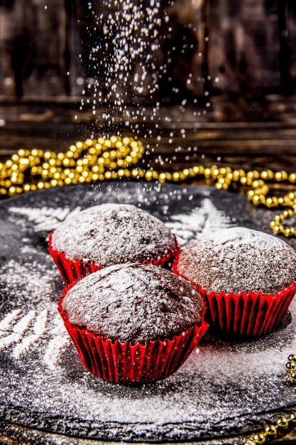 Photo muffins au chocolat sur fond sombre avec du sucre glace