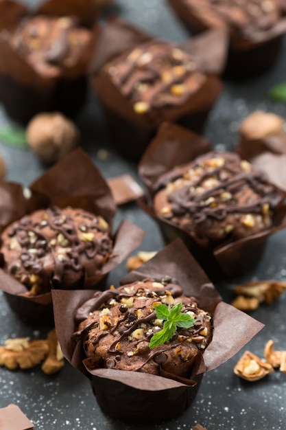 Muffins au chocolat avec des noix et des pépites de chocolat sur une table sombre